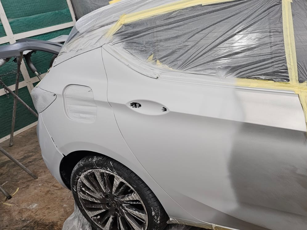 Bodywork repair in progress in the spray booth — welded panel repair and colour-matched primer